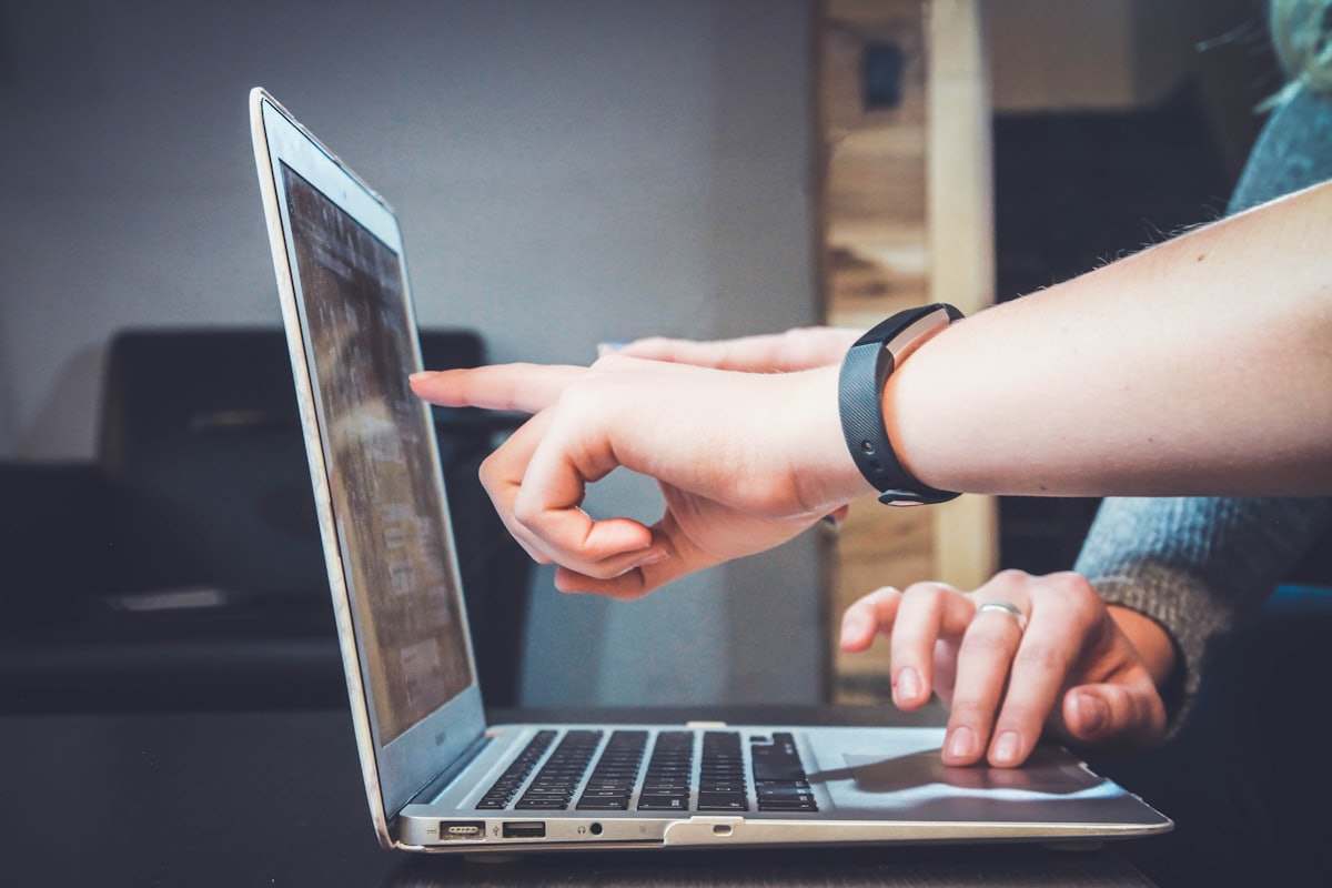 Due colleghe davanti a un computer portatile, una indica lo schermo all'altra
