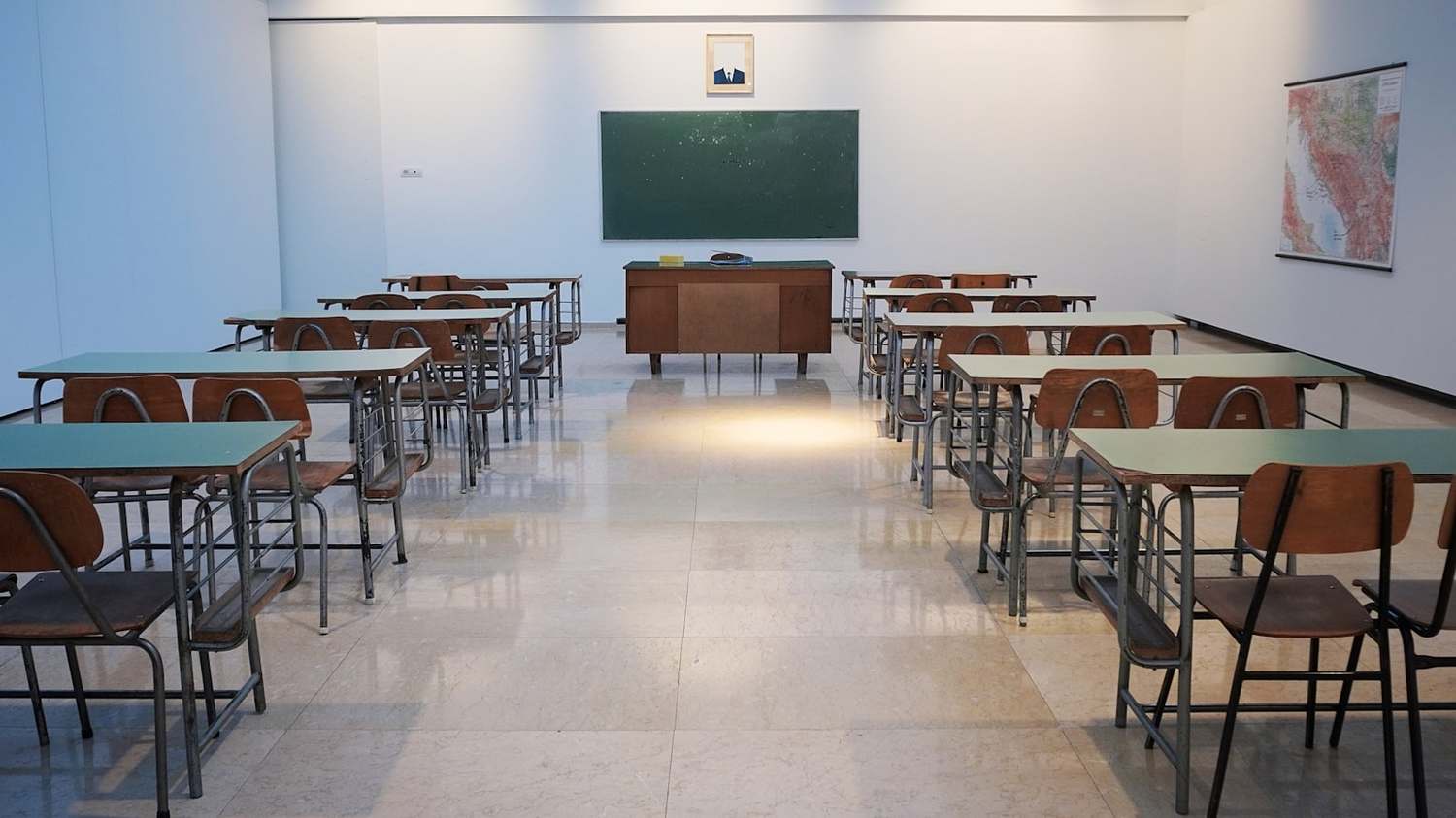 Aula scolastica vuota con banchi allineati e lavagna verde